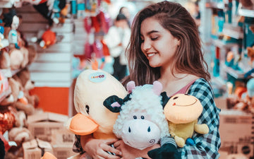 Young woman hugging an armful of plush toys in a toy store